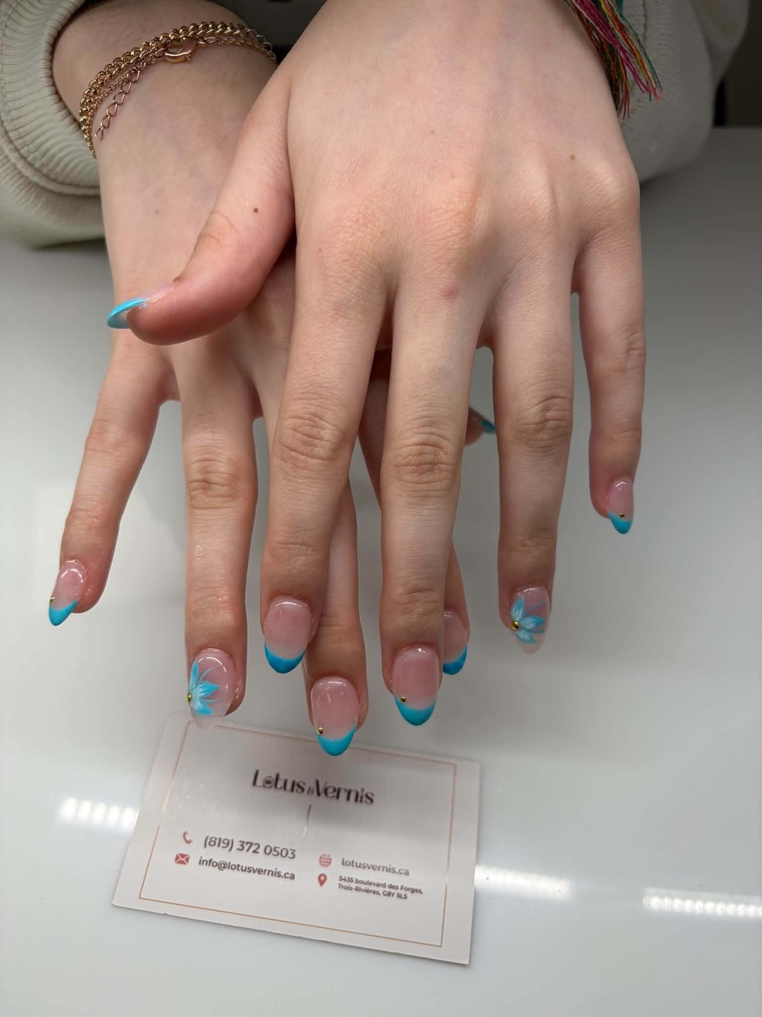 Pose d'ongles amande, French turquoise avec ongles fleuris bleus et touches dorées