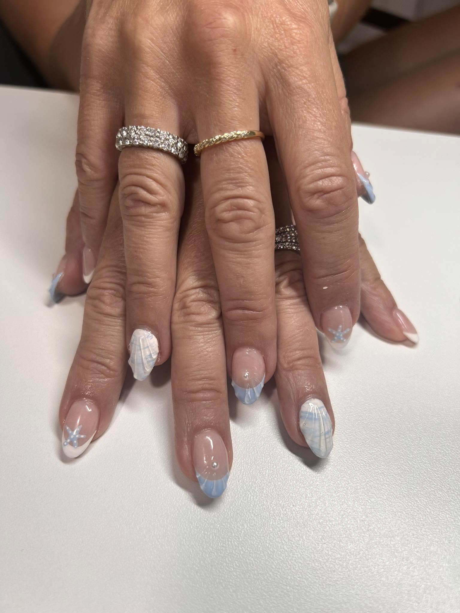 Pose d'ongles ovale, French marbré bleu et blanc orné de coquillages et d'une étoile de mer