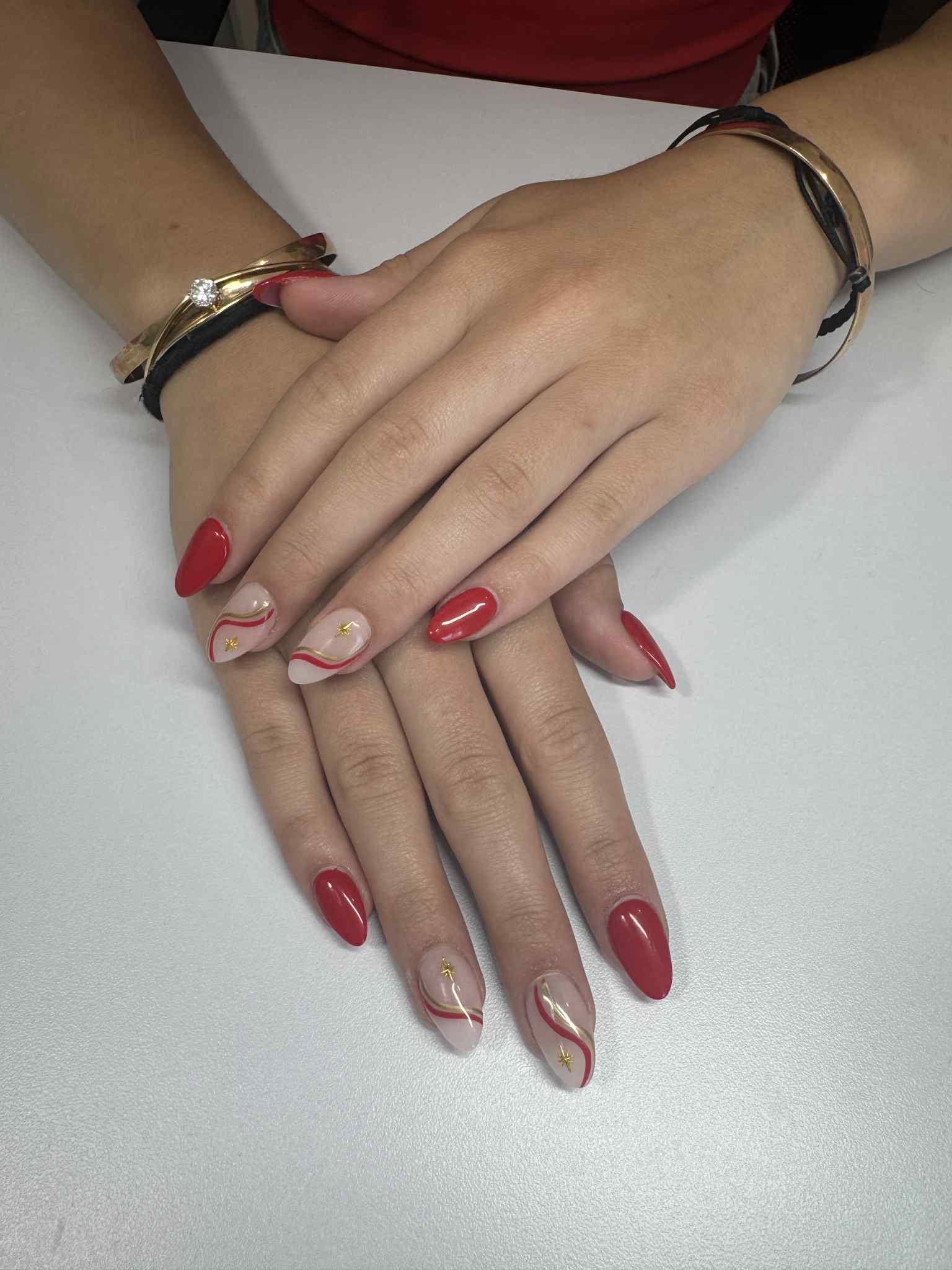 Pose d'ongles amande, vernis rouge avec volutes nude et fines lignes dorées