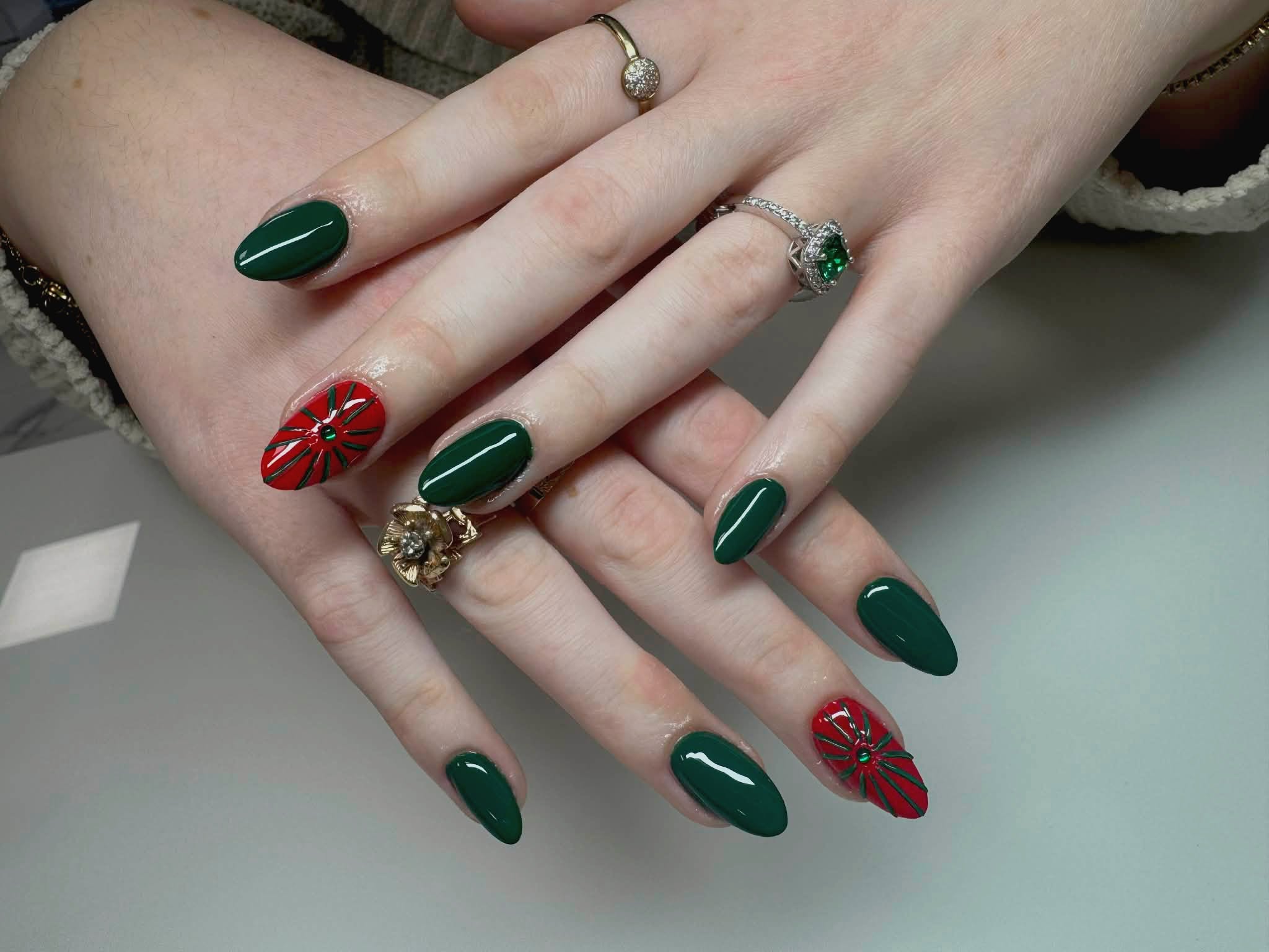 Pose d'ongles amande, vernis vert forêt avec fleurs rouges festives